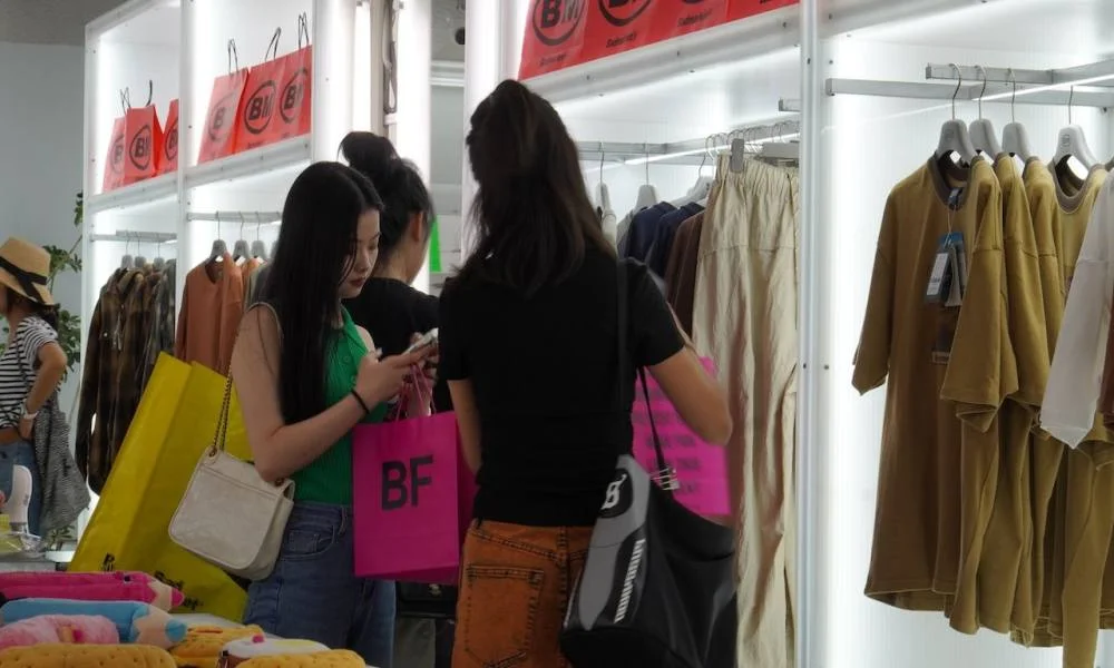 Chinese Gen Z women shopping for clothing while checking smartphones inside a retail fashion store
