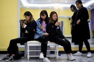 Chinese Gen Z teenagers using smartphones together illustrating the digital lifestyles of Chinese Gen Z consumers