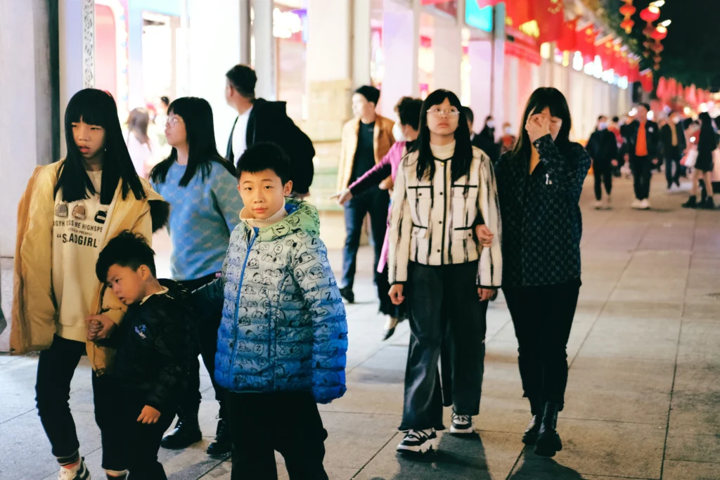 Chinese families and young consumers shopping and walking in a busy retail street at night