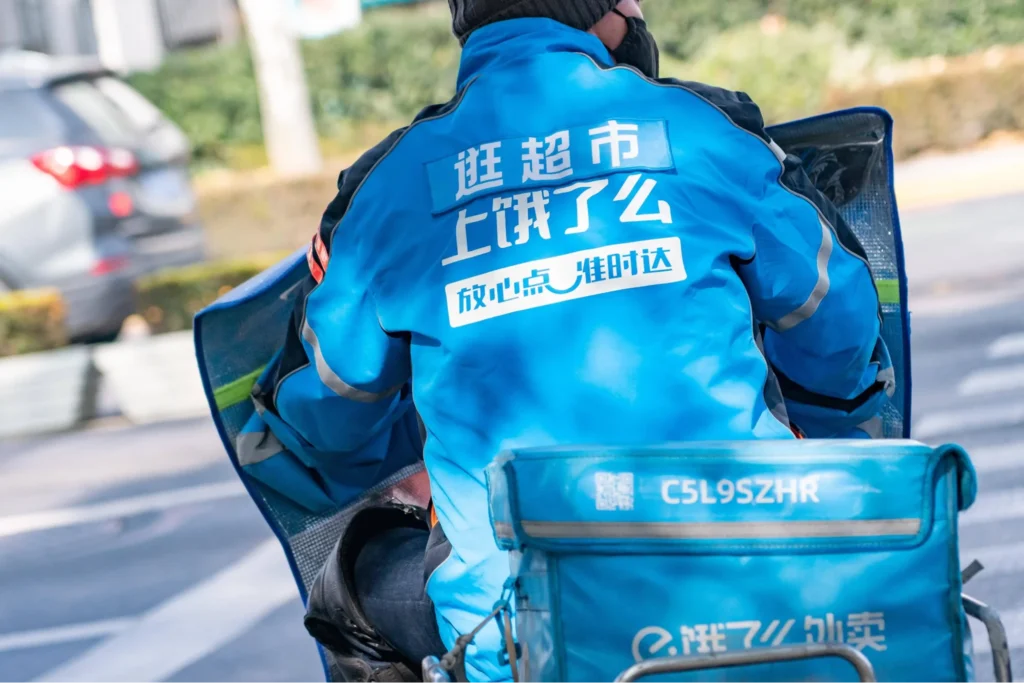 Ele.me delivery rider wearing blue uniform on a scooter representing China’s food delivery platforms featured in social media marketing campaigns.
