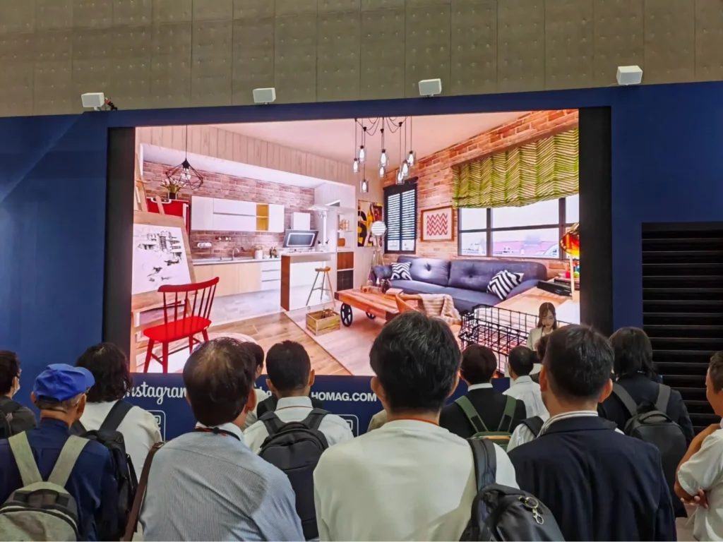 Audience viewing large screen 3D interior design visualization at industry exhibition