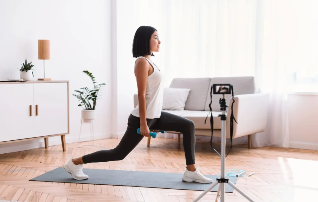 Female fitness influencer recording home workout video with dumbbells for social media audience