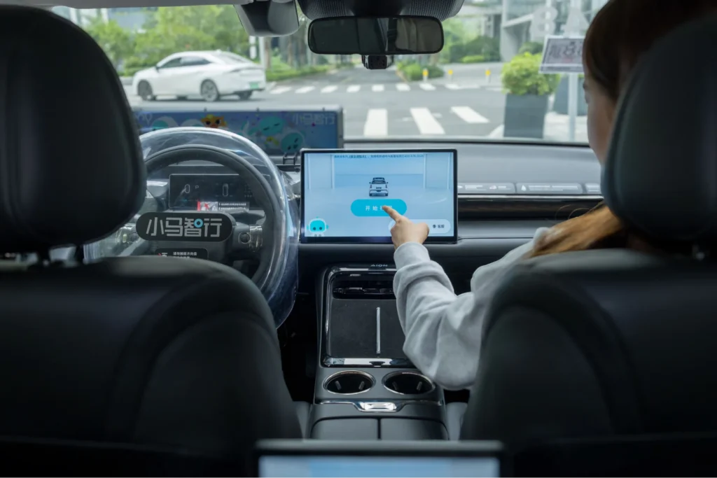 Passenger interacting with Pony AI robotaxi touchscreen interface inside autonomous vehicle cabin