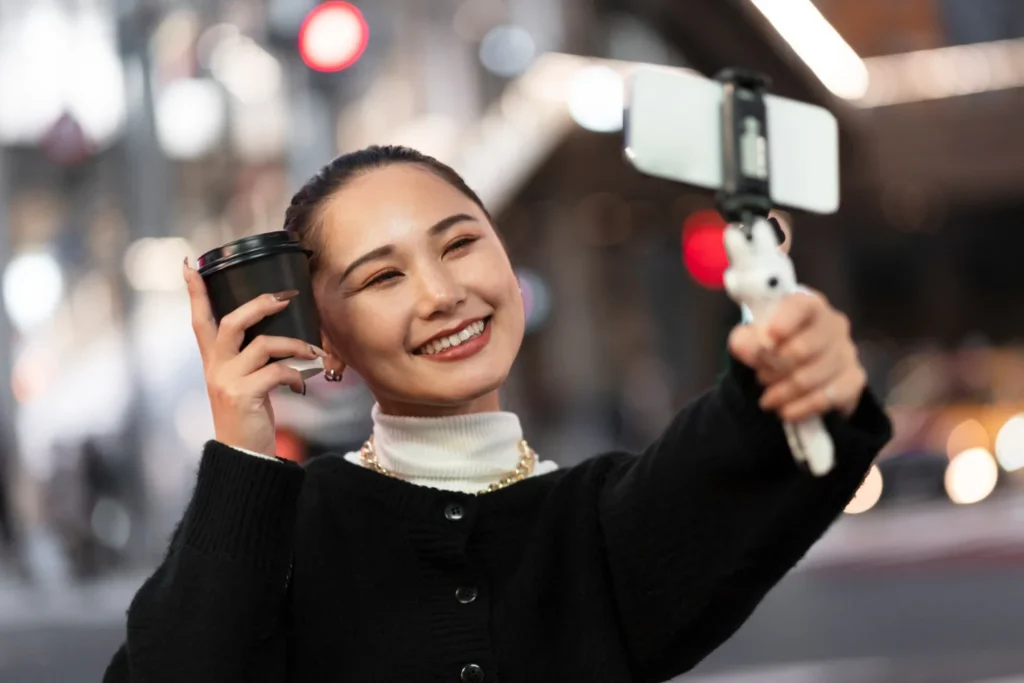 Lifestyle influencer taking selfie with coffee on city street, creating casual social media content