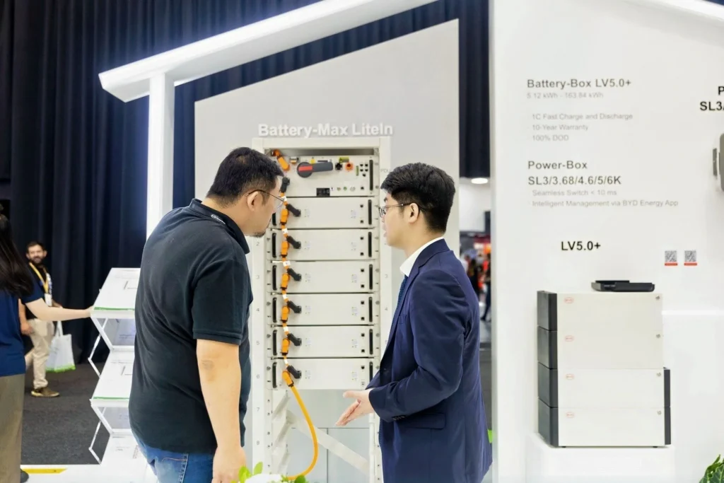 Two attendees examining BYD Blade Battery and residential energy storage technology at an industry event.