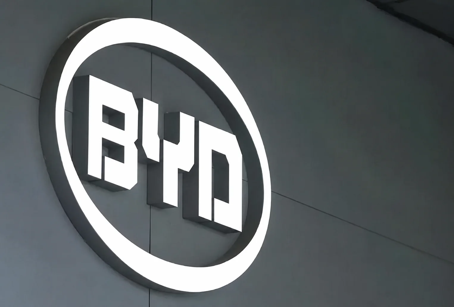 Illuminated BYD company logo mounted on a modern corporate building exterior.
