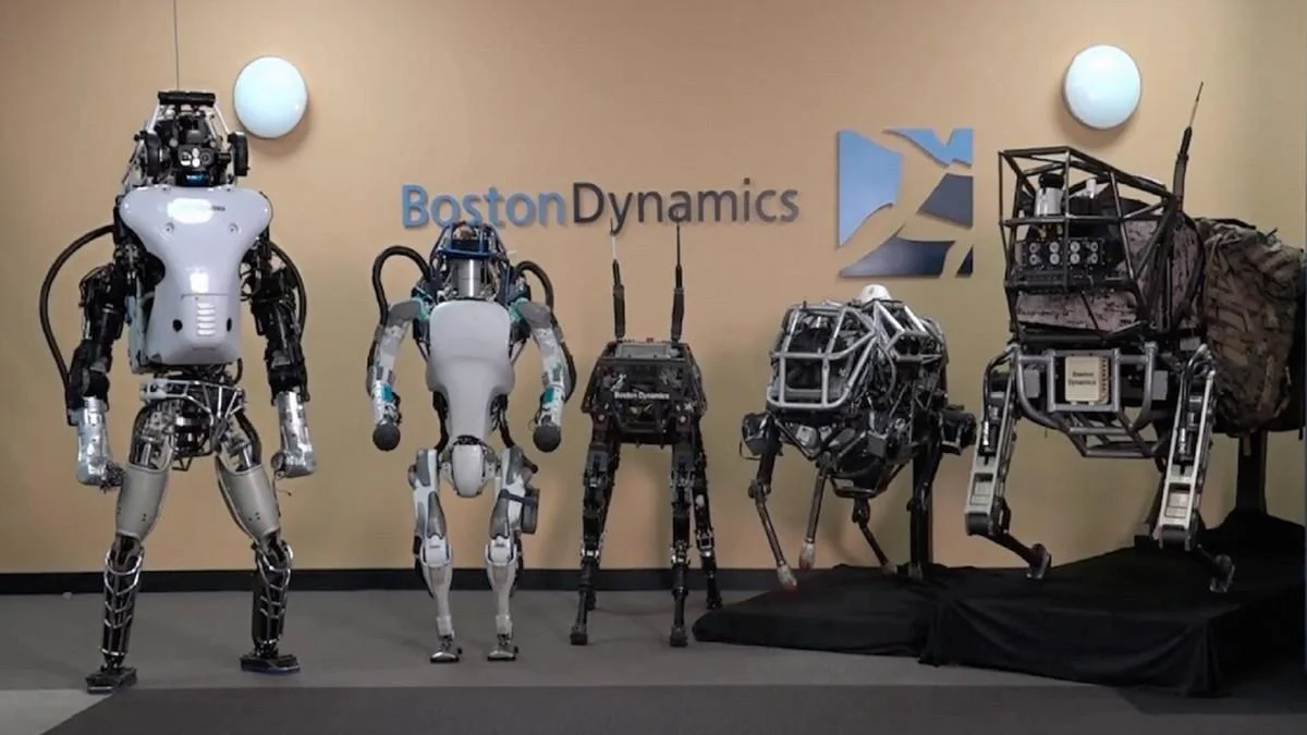 Boston Dynamics humanoid and quadruped robots displayed together inside the robotics research facility.
