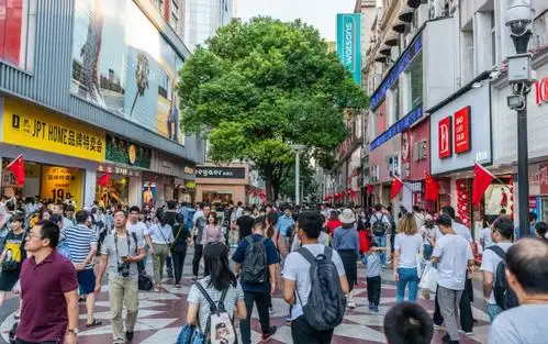 Crowds walk through a major shopping and retail district lined with stores and digital signage in China.