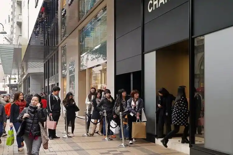 Shoppers wait outside a luxury fashion store in Hong Kong’s high-end retail district.