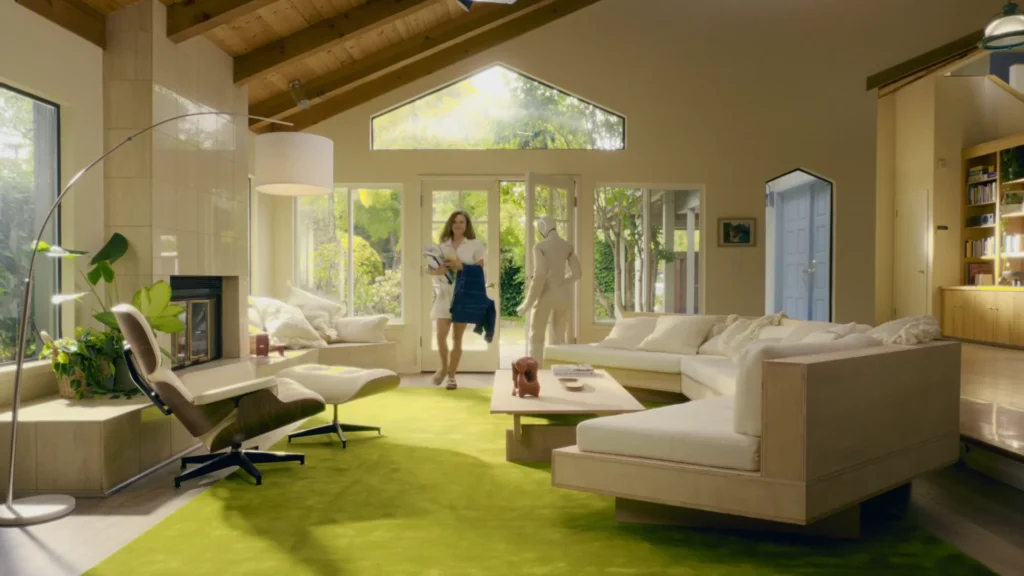 NEO humanoid robot assisting a woman entering a modern home with bags and clothing