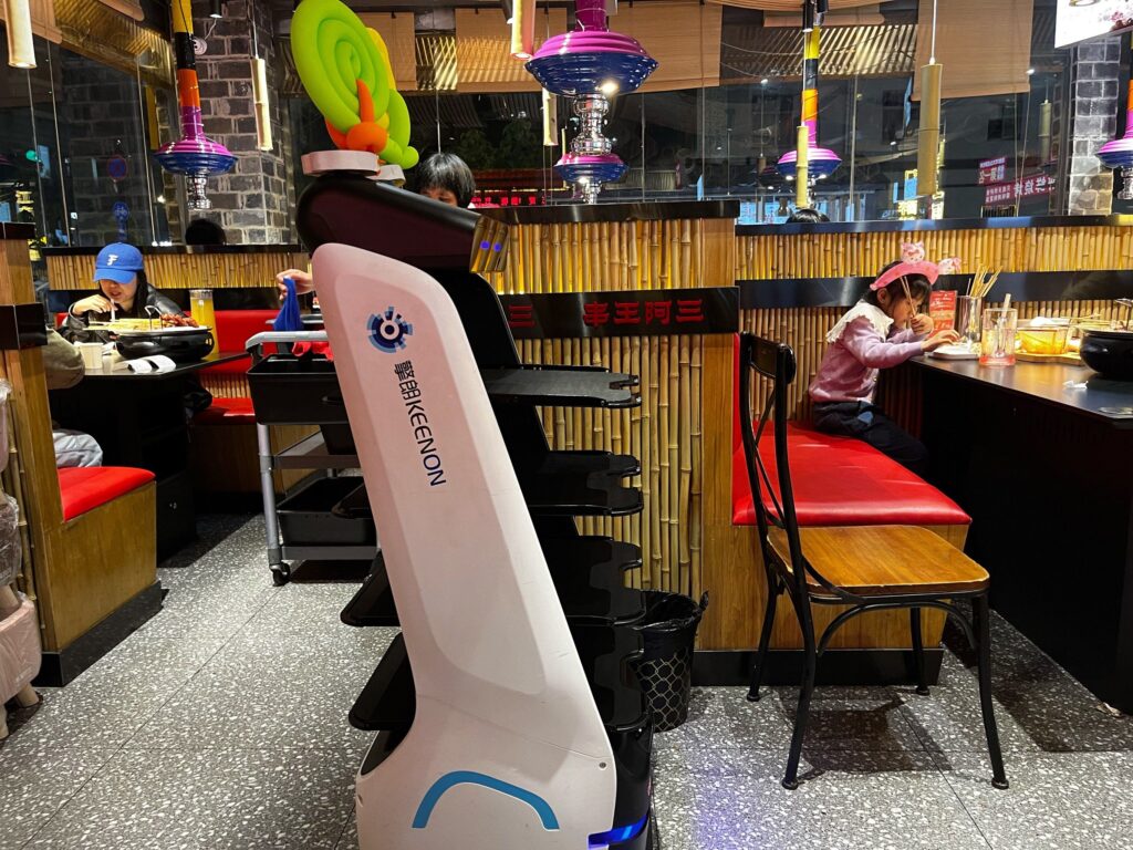 Keenon delivery robot placing a dish on a restaurant table autonomously