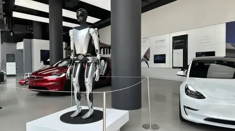 Tesla Optimus humanoid robot displayed inside a Tesla showroom beside electric vehicles
