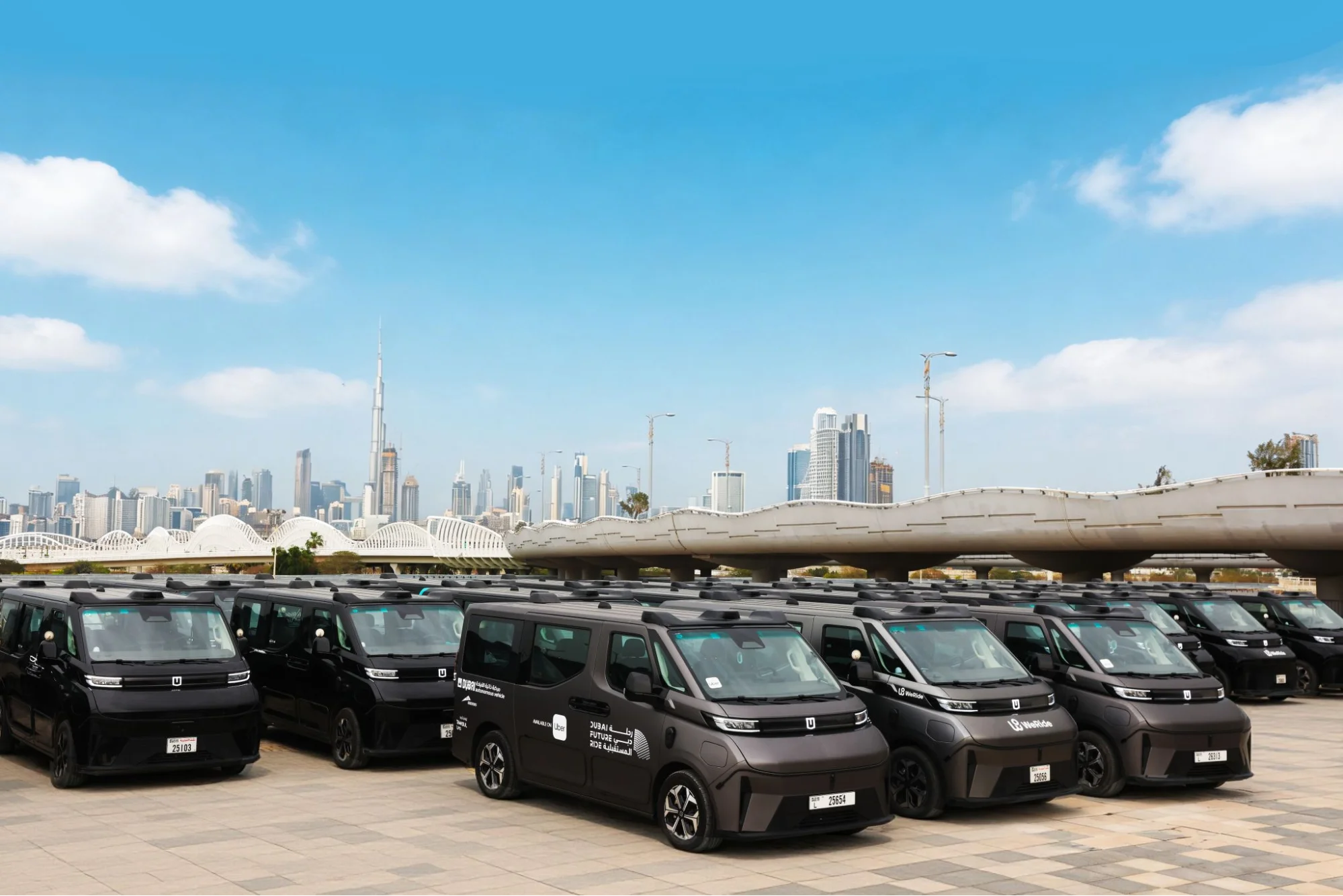 WeRide robotaxi fleet parked in city with skyline, showing large-scale autonomous vehicle deployment