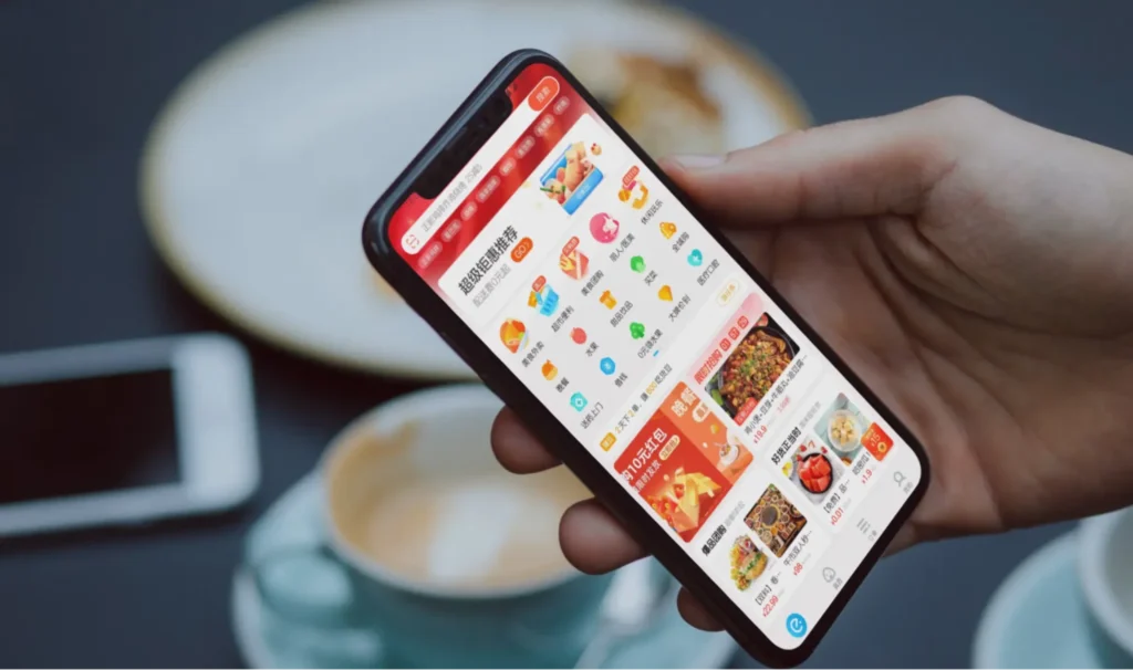 Close-up of smartphone showing Pinduoduo app interface with product listings and categories