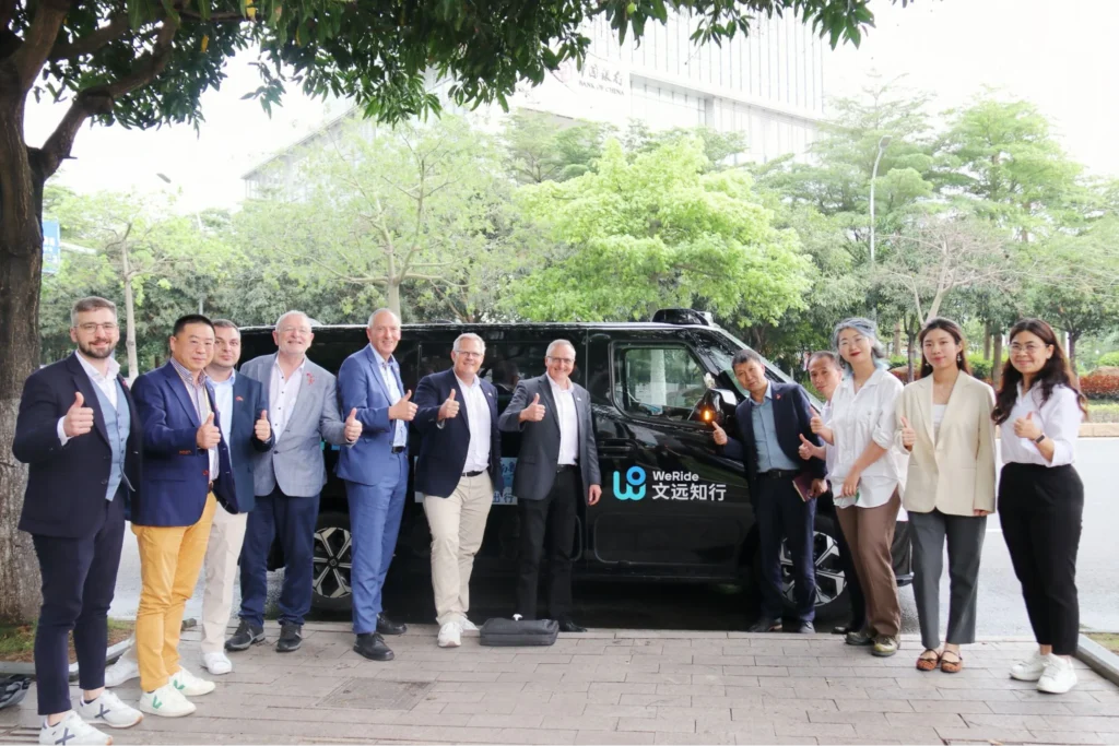 WeRide team and partners posing with robotaxi vehicle during international collaboration