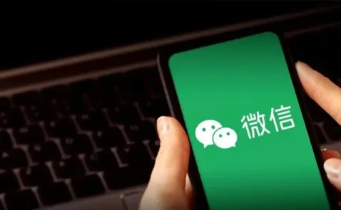 Smartphone displaying WeChat app interface held in hand with keyboard in background