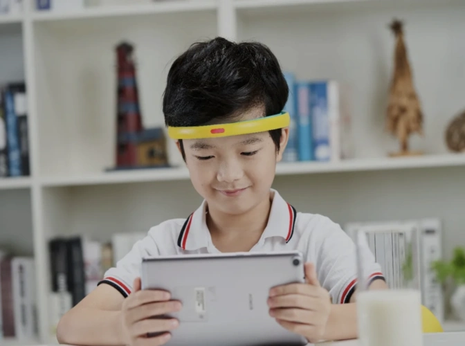 Child using tablet while wearing BrainCo EEG headband for focus and attention training