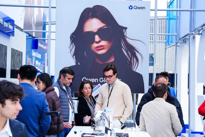 People exploring Qwen AI technology at a tech exhibition booth with product demonstrations