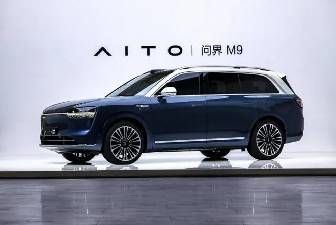 Blue AITO M9 SUV displayed on a studio platform with clean branding background.