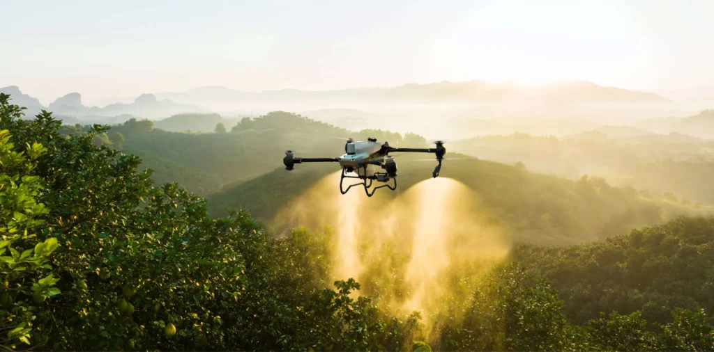Drone spraying crops over green farmland
