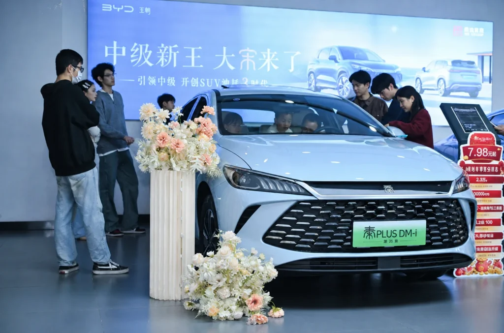 Customers exploring a BYD sedan inside a branded automotive showroom in China.
