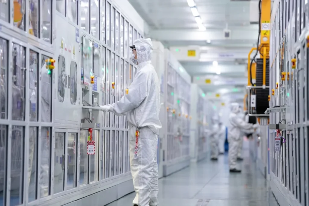 Technicians in cleanroom suits operating automated equipment inside a CATL battery production facility in China.