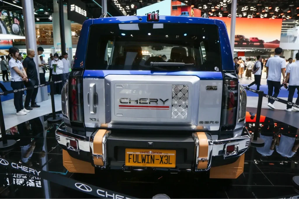 Chery vehicle display at indoor automotive event with attendees viewing cars under showroom lighting
