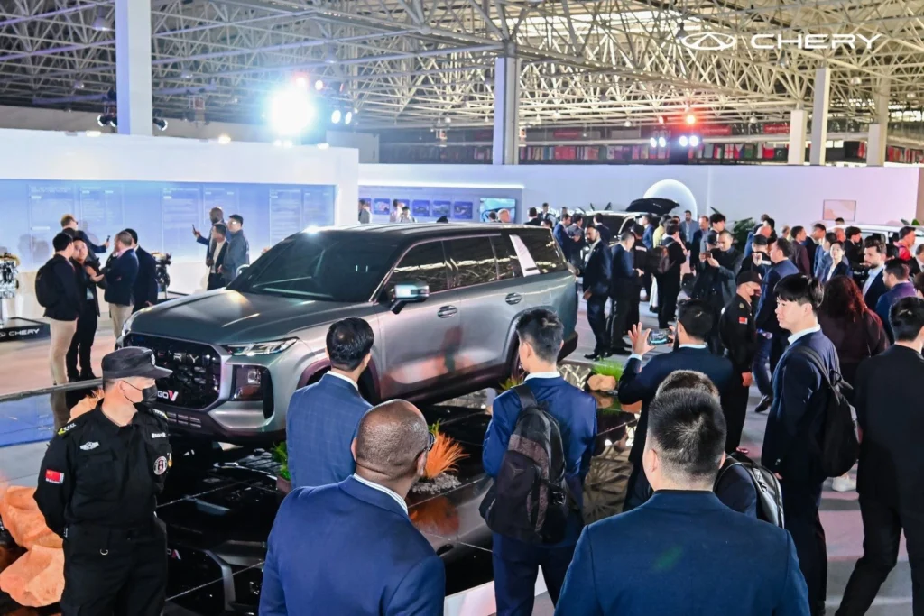 Chery SUV showcased at motor show with crowd of visitors observing the vehicle