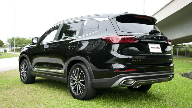 Black Chery Tiggo SUV parked on grass, rear angle view with chrome exhaust details.