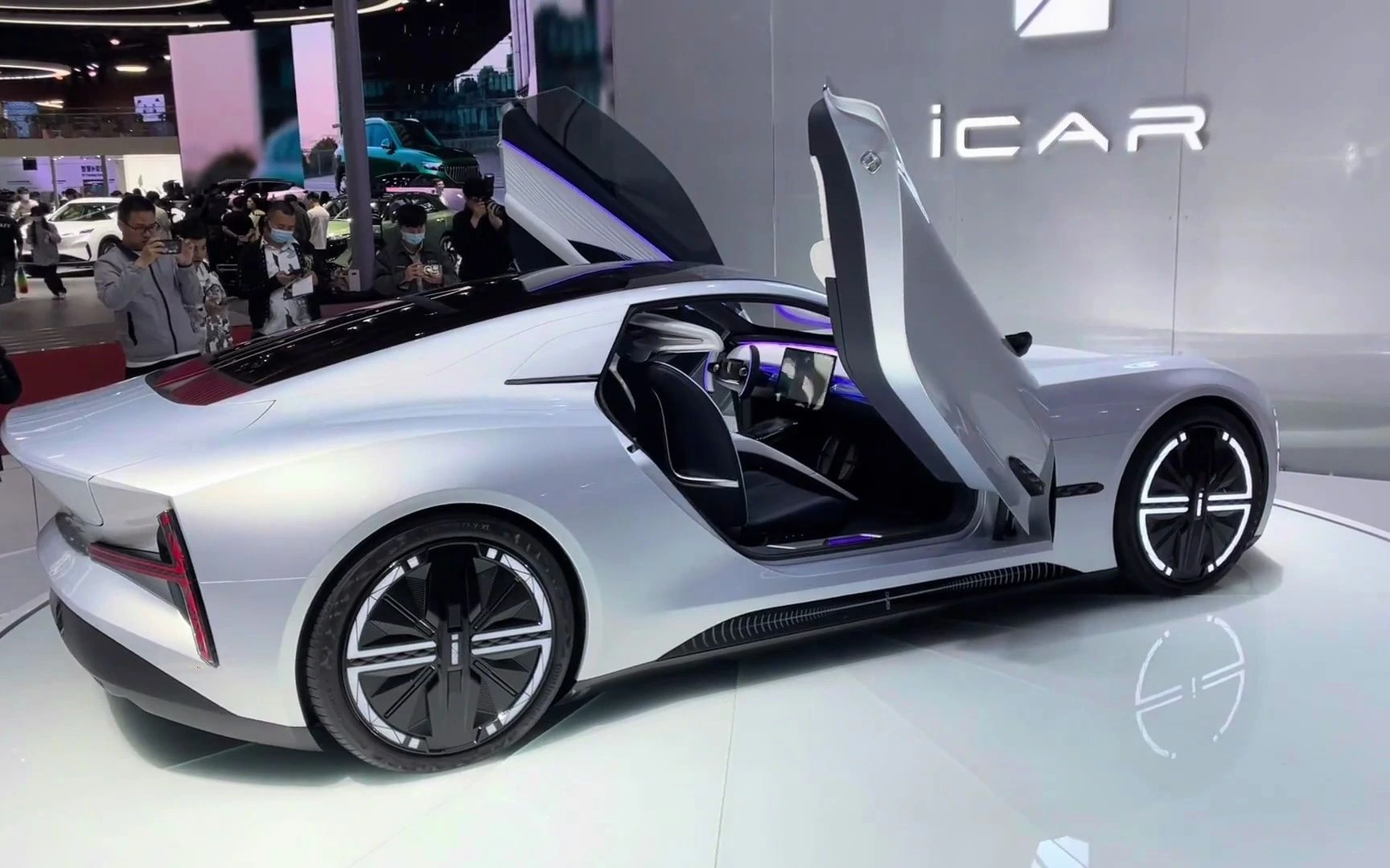 Futuristic Chery iCAR electric car with gullwing doors open, displayed at auto show.