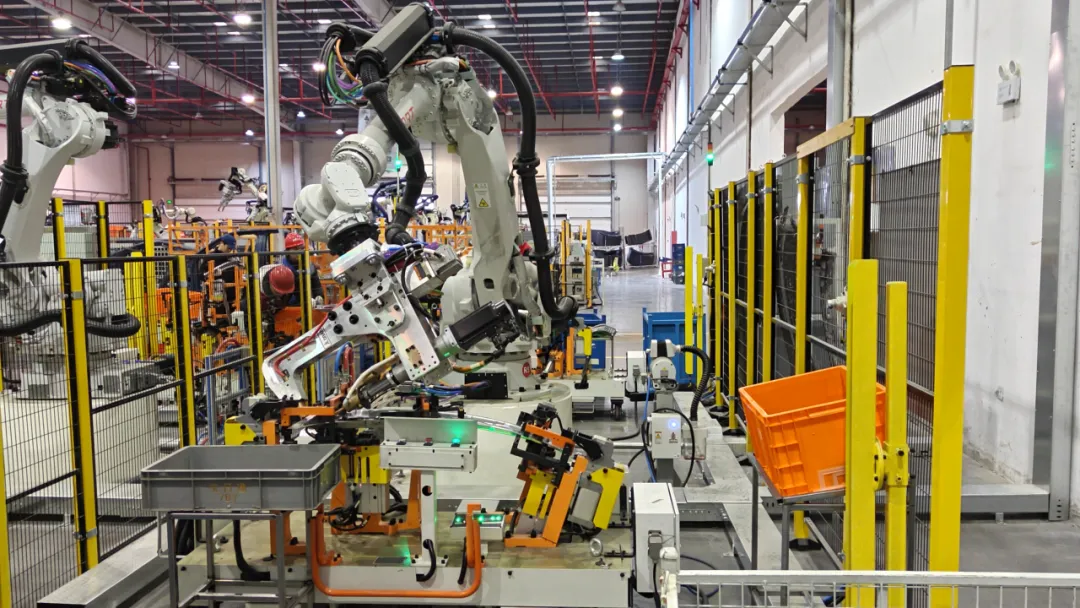 White industrial robotic arm operating inside safety-caged manufacturing cell