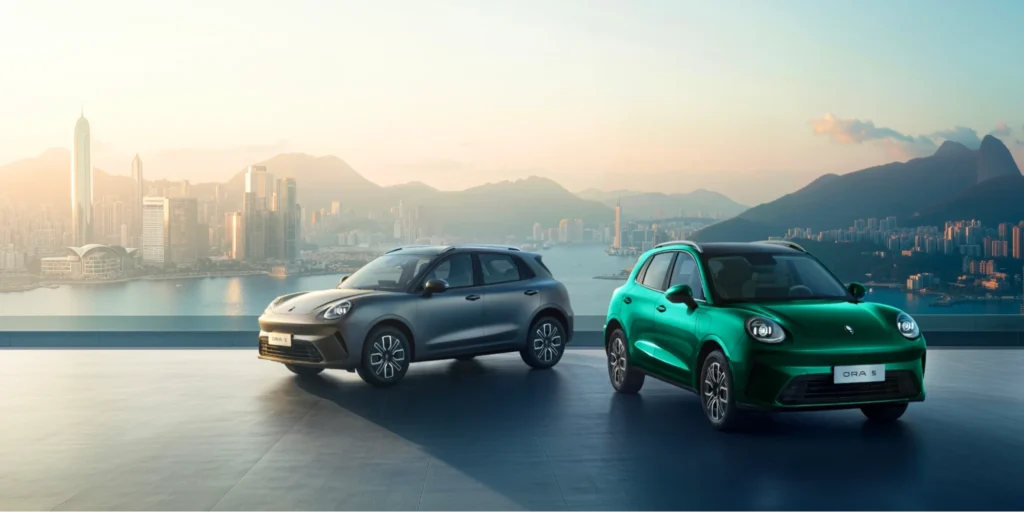 Two GWM ORA 03 electric cars with a city skyline background