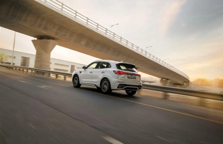 White Hongqi SUV moving on a highway bridge during golden hour.