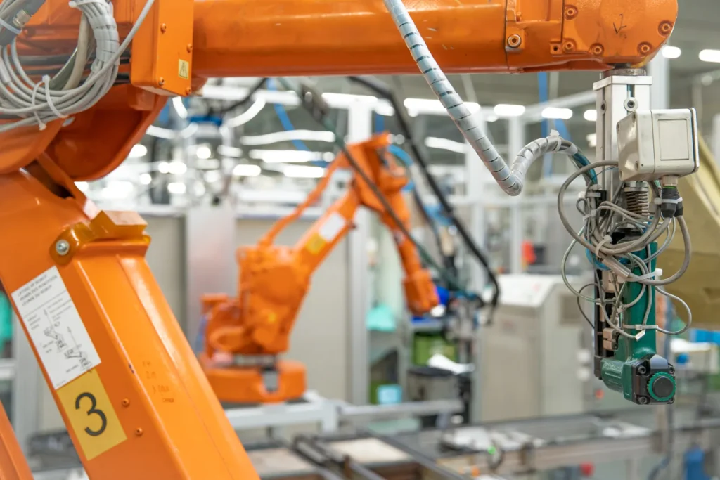 Orange industrial robotic arms operating in a factory automation assembly line.