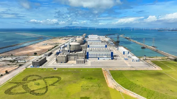 Nuclear power plant near blue sea and offshore wind turbines