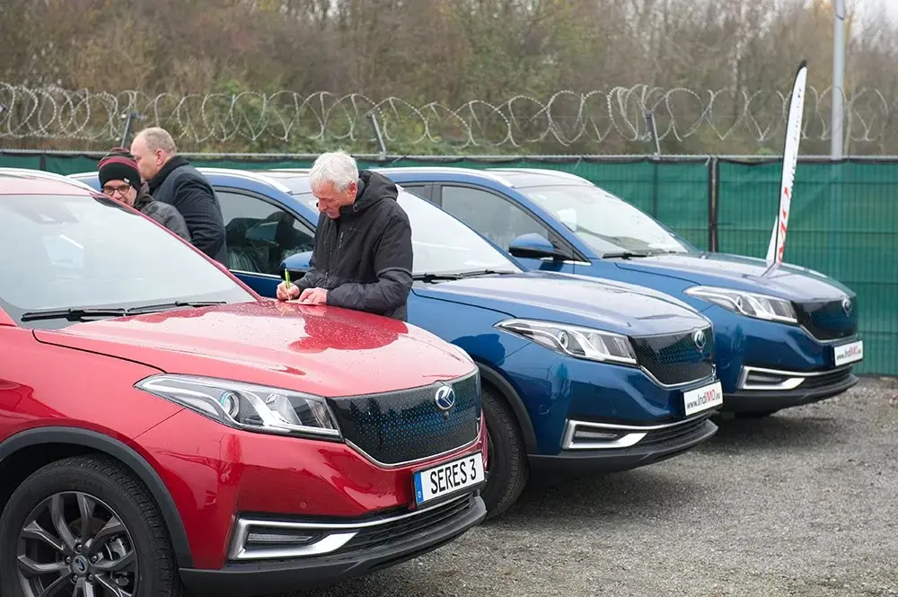 Row of red and blue SERES SUVs parked outdoors with a person inspecting a vehicle.