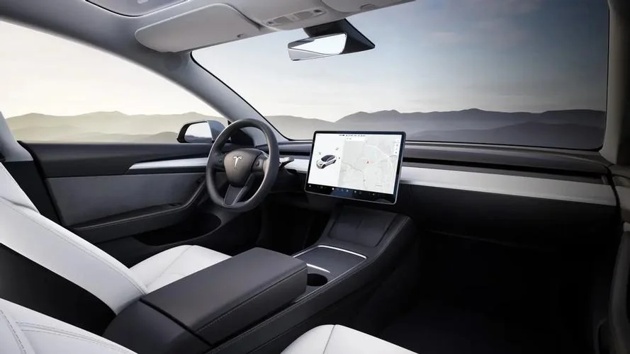Minimalist Tesla electric vehicle interior with central touchscreen and panoramic windshield.