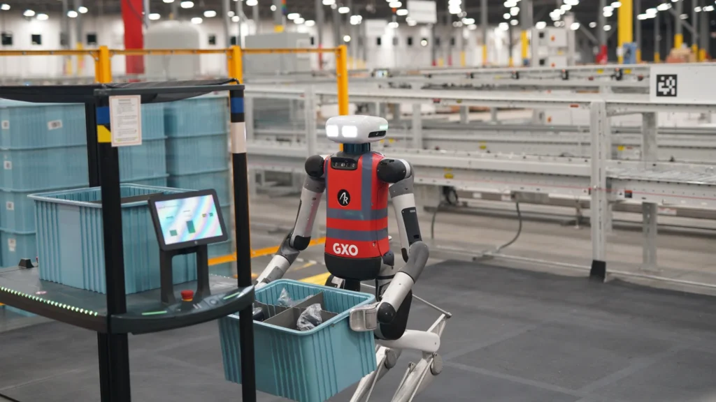 Humanoid robot sorting inventory bins during a warehouse automation deployment at a GXO logistics facility.