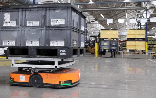 AGV carrying large bins inside an industrial warehouse