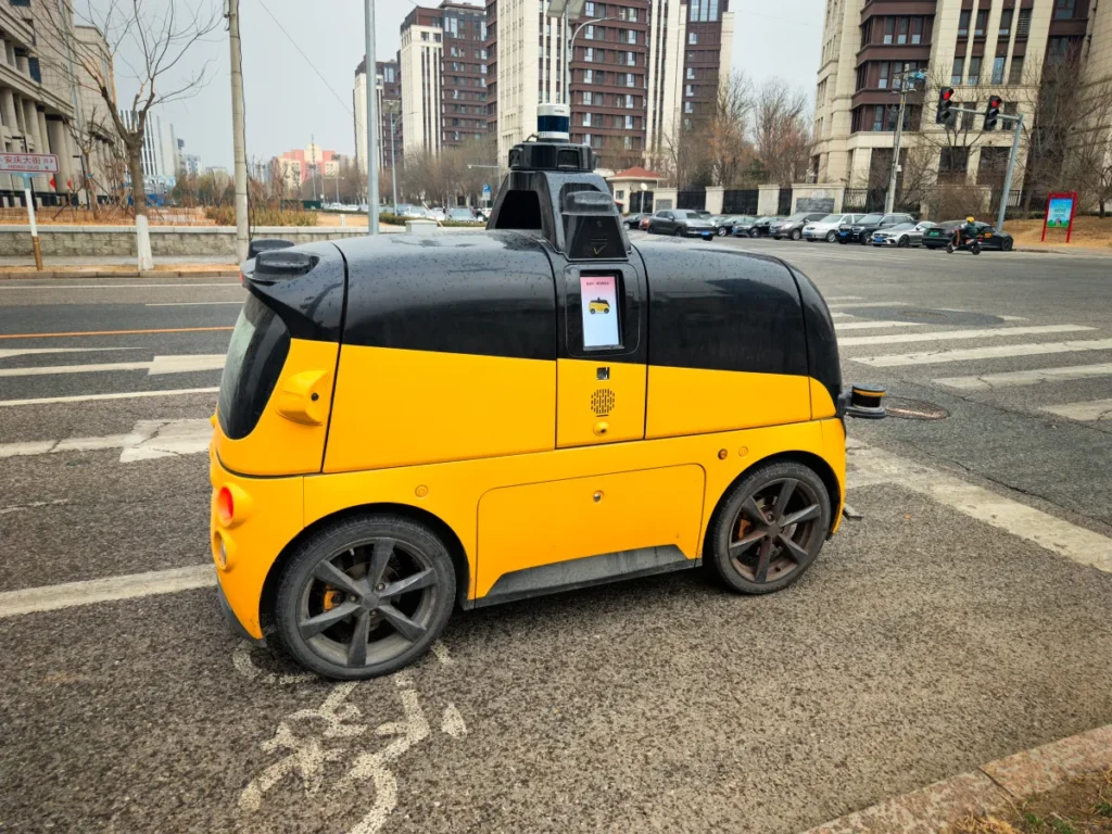 Yellow delivery robot parked near crosswalk