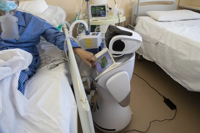 Hospital care robot assisting a patient beside the bed.