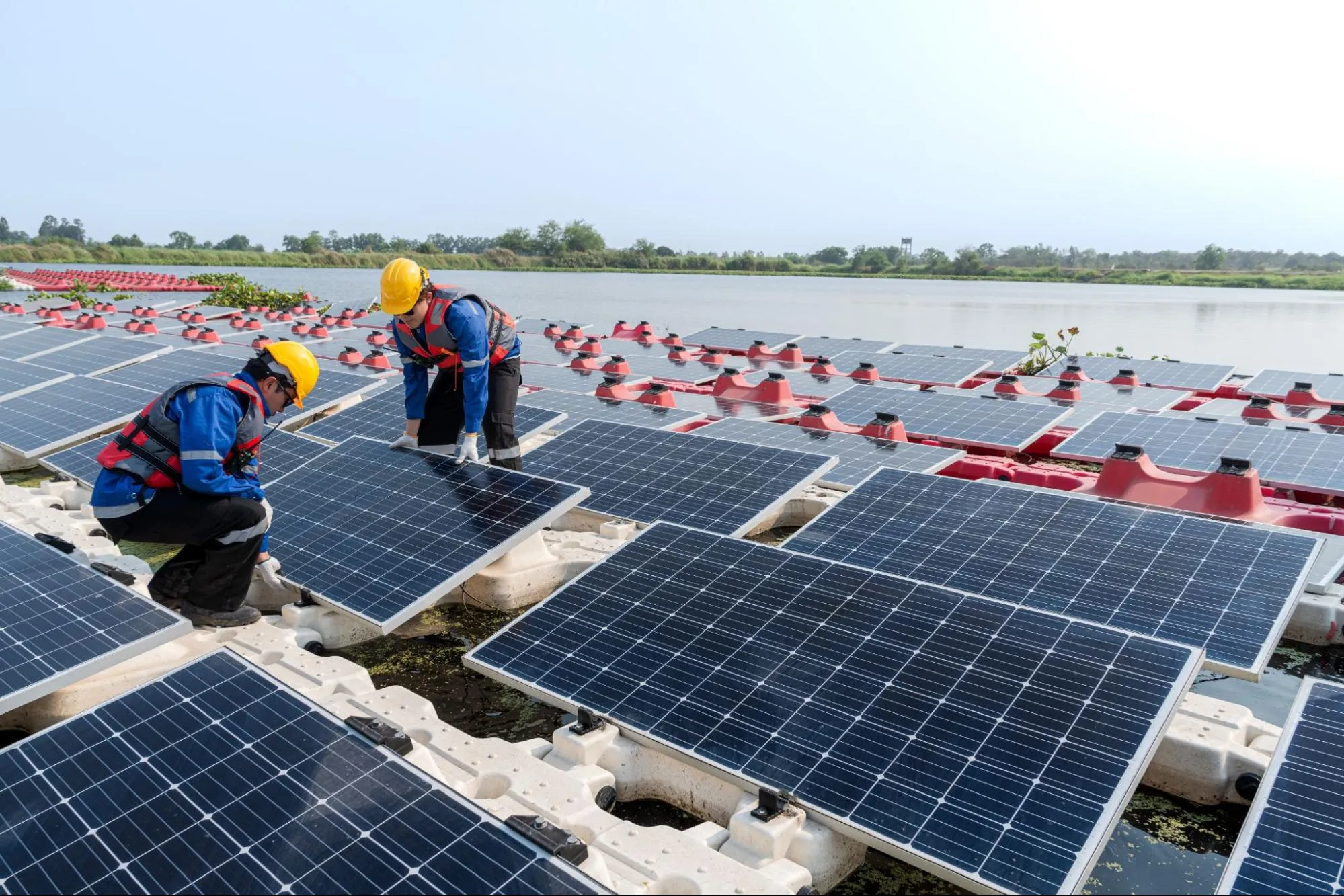 Workers installing floating solar panels on water