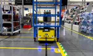 Yellow AGV moving a cart on factory guide path