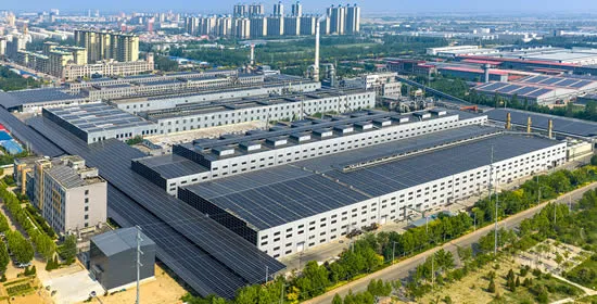Large industrial building with rooftop AIKO solar panel installation.