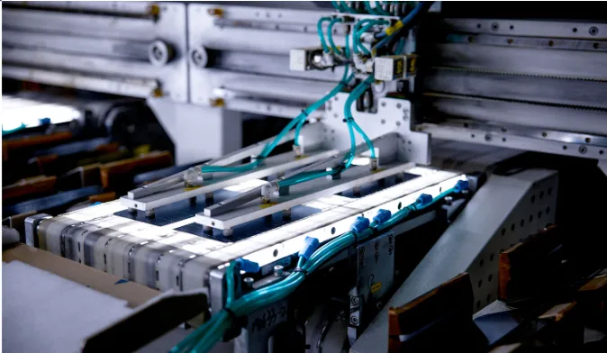 Close up of automated machinery working on solar module components inside a production line.