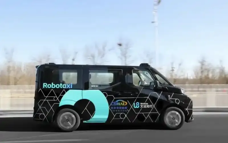 Black robot taxi driving on an urban road