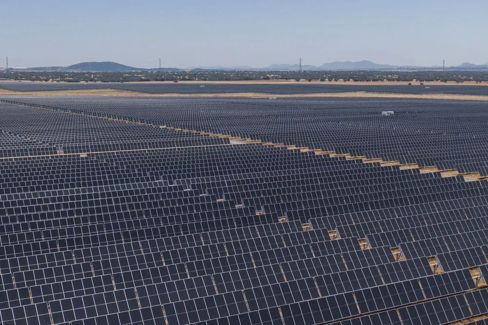 Wide view of a massive solar farm with rows of photovoltaic panels across open land.