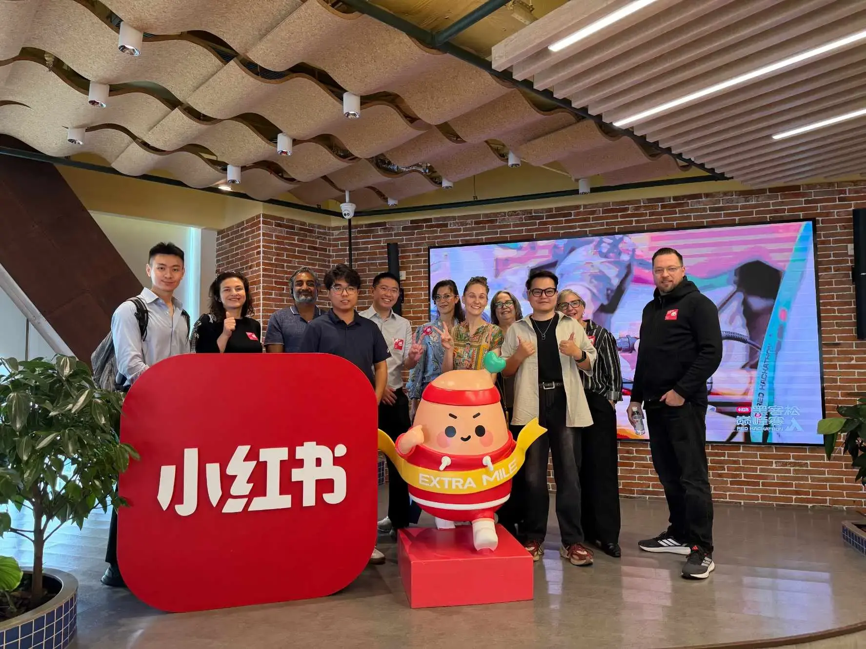 Visitors gathered beside a red Xiaohongshu display during a company visit.