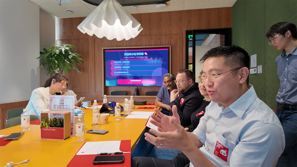 A visiting group stands beside the BrainCo logo in a company lobby.